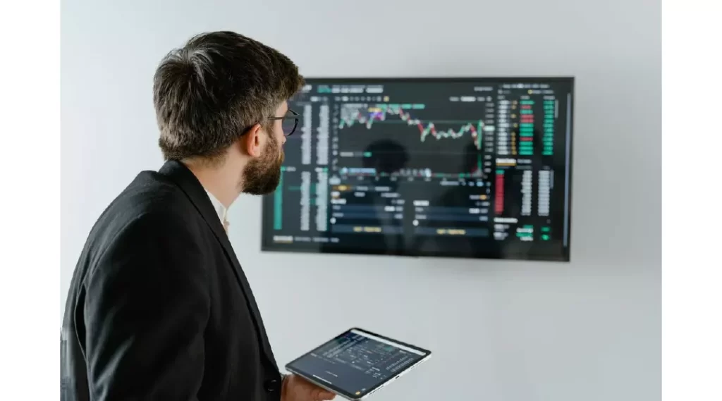 Man in Black Suit Holding a Digital Tablet and Looking At Data On Screen